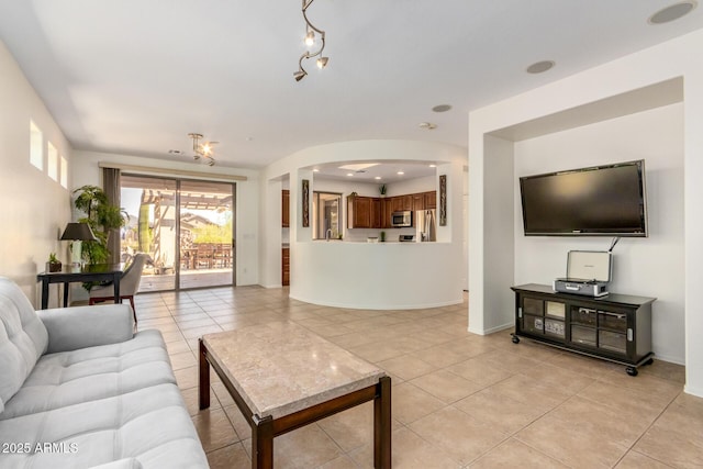 living area featuring arched walkways, baseboards, and light tile patterned floors