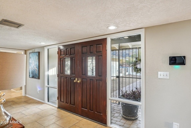 tiled entryway featuring a textured ceiling