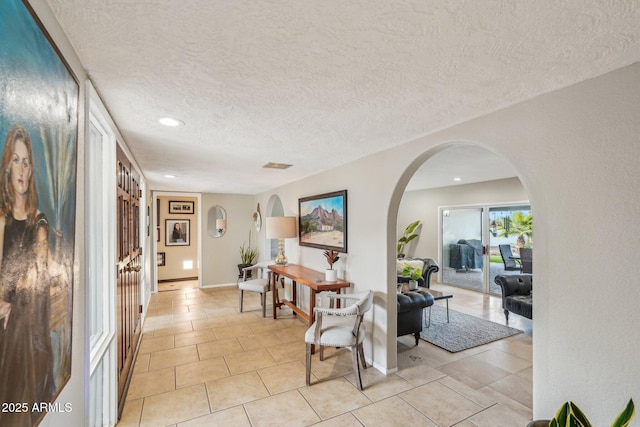 hallway with light tile patterned floors and a textured ceiling