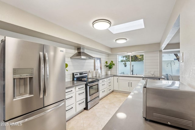 kitchen featuring stainless steel appliances, sink, wall chimney range hood, white cabinetry, and light tile patterned flooring