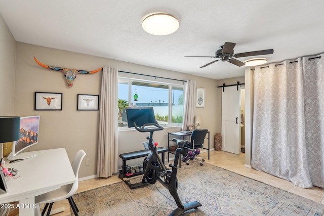 tiled office space featuring a barn door and ceiling fan