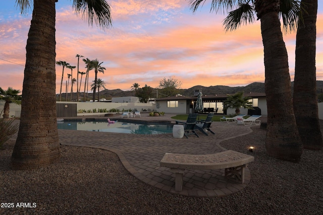 pool at dusk with a patio area