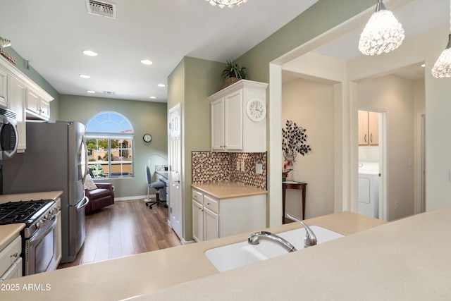 kitchen with visible vents, white cabinetry, stainless steel appliances, light countertops, and decorative backsplash