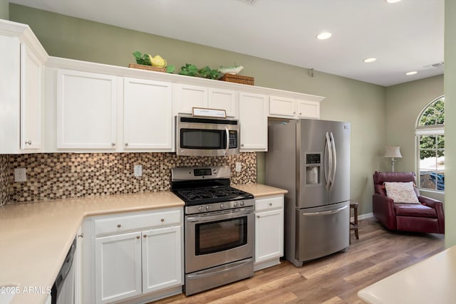 kitchen with light countertops, decorative backsplash, light wood-style flooring, appliances with stainless steel finishes, and white cabinets