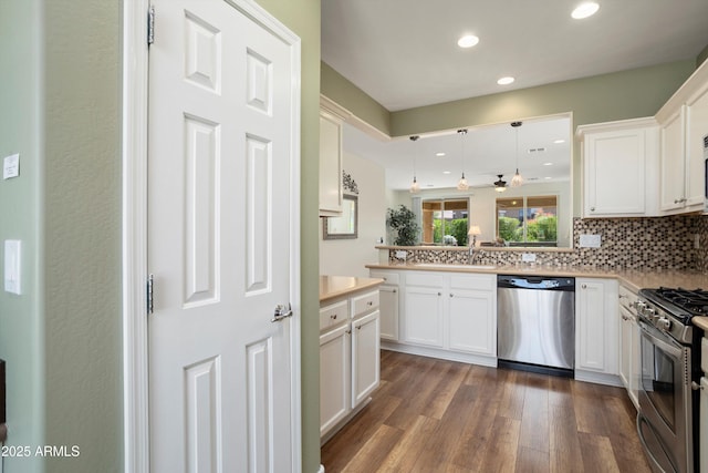 kitchen featuring dark wood-type flooring, light countertops, decorative backsplash, appliances with stainless steel finishes, and white cabinetry