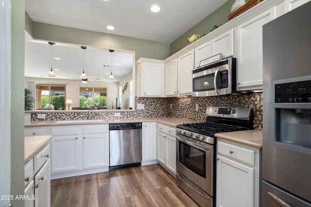 kitchen with dark wood-style flooring, light countertops, white cabinets, appliances with stainless steel finishes, and backsplash