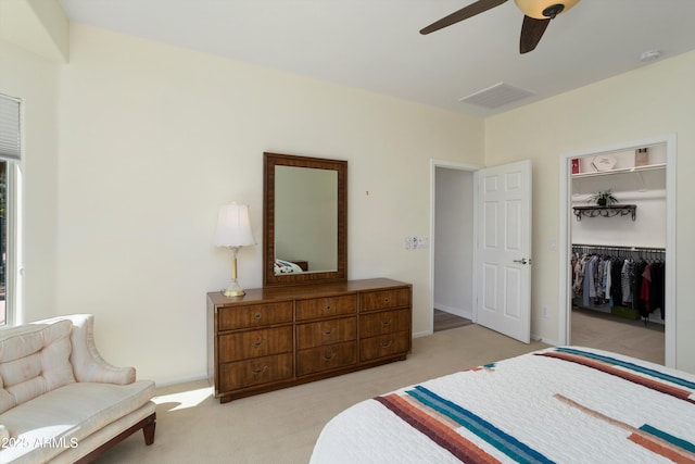 bedroom with a ceiling fan, visible vents, light colored carpet, and a closet