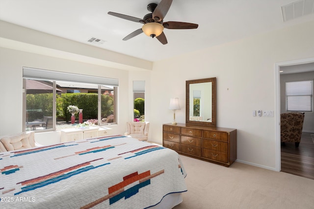 carpeted bedroom with a ceiling fan, baseboards, and visible vents