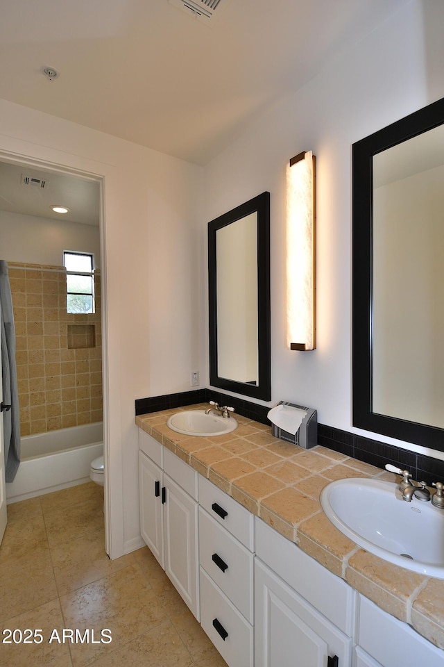 full bathroom featuring toilet, vanity, and tiled shower / bath