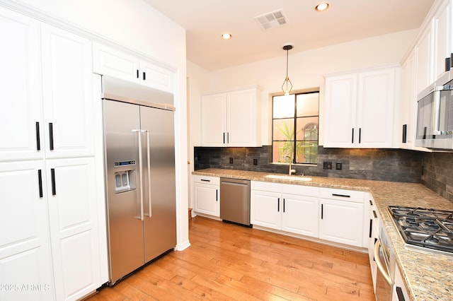 kitchen featuring decorative light fixtures, sink, white cabinetry, and stainless steel appliances