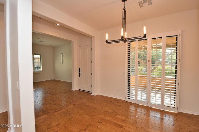 unfurnished dining area featuring hardwood / wood-style floors and a notable chandelier