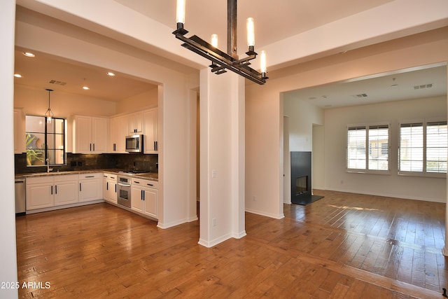 kitchen with white cabinets, backsplash, appliances with stainless steel finishes, and a chandelier