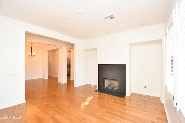 unfurnished living room with light hardwood / wood-style flooring and a notable chandelier