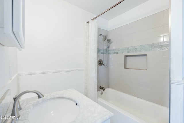 bathroom with a sink, a wainscoted wall, and shower / bath combo