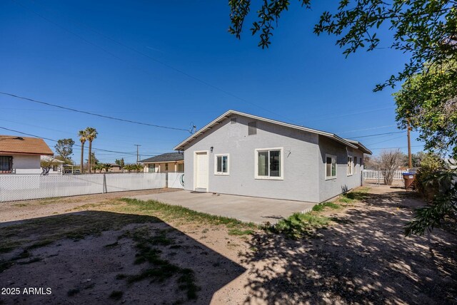 back of house with stucco siding, a patio, and a fenced backyard