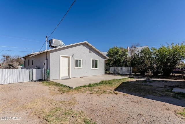 rear view of property featuring stucco siding, a patio, central AC, and fence