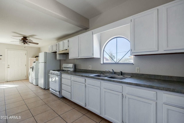 kitchen with a sink, under cabinet range hood, gas range gas stove, dark countertops, and ceiling fan