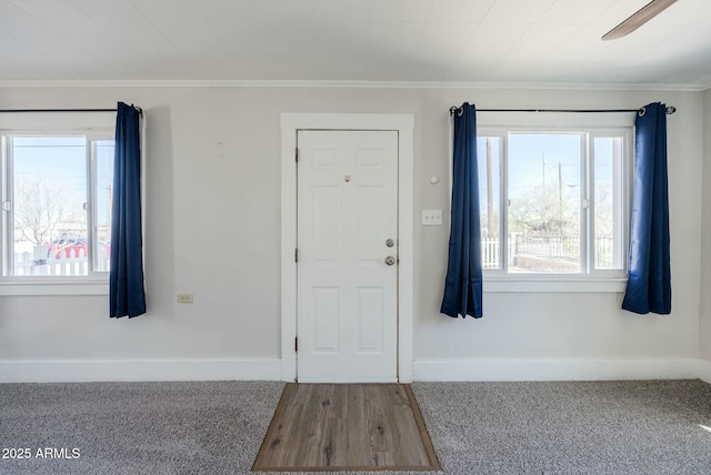 foyer with carpet flooring, a ceiling fan, baseboards, and ornamental molding