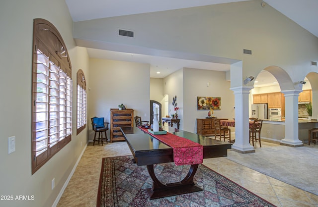 dining space featuring visible vents, light carpet, high vaulted ceiling, decorative columns, and baseboards