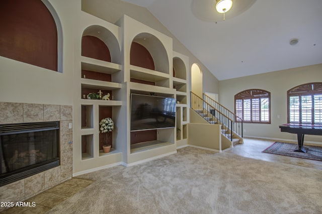 unfurnished living room with baseboards, carpet, built in features, stairway, and a tile fireplace