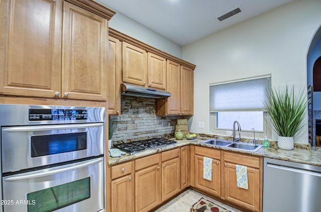 kitchen featuring visible vents, under cabinet range hood, a sink, appliances with stainless steel finishes, and light stone countertops