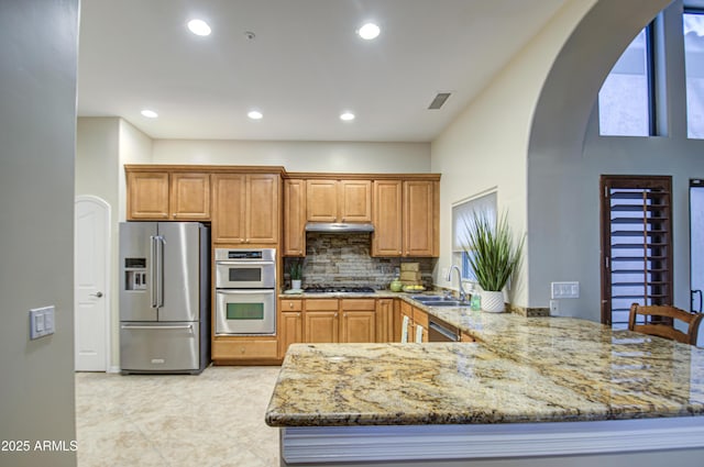 kitchen featuring light stone countertops, visible vents, a sink, stainless steel appliances, and under cabinet range hood