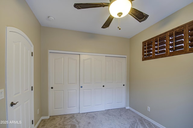 unfurnished bedroom with a closet, baseboards, carpet, and a ceiling fan