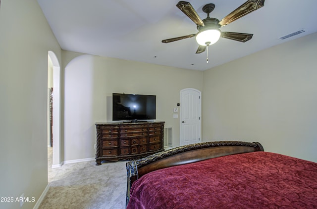 carpeted bedroom featuring visible vents, arched walkways, baseboards, and ceiling fan