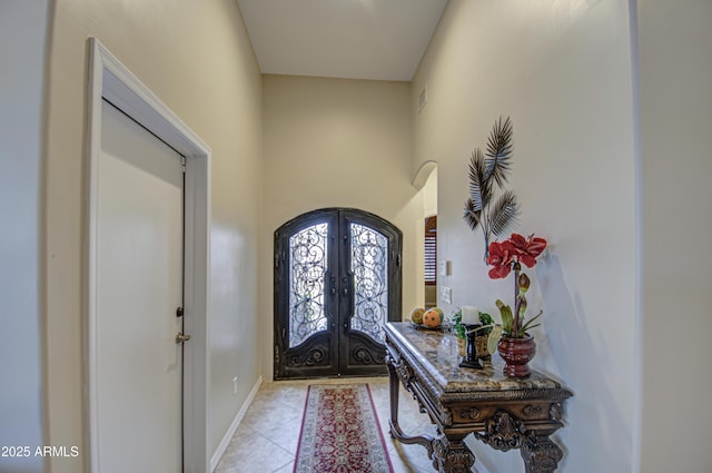 foyer entrance with visible vents, french doors, arched walkways, light tile patterned flooring, and baseboards