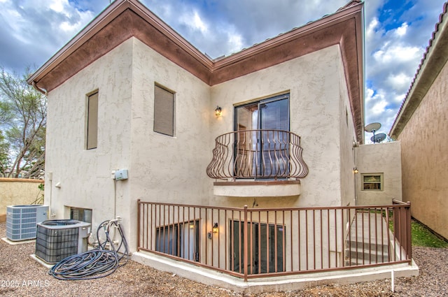 rear view of property featuring central air condition unit and stucco siding