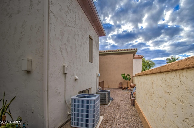 view of home's exterior with stucco siding, central AC, and a tiled roof