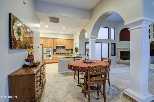 dining area featuring visible vents, ornate columns, recessed lighting, arched walkways, and a high end fireplace