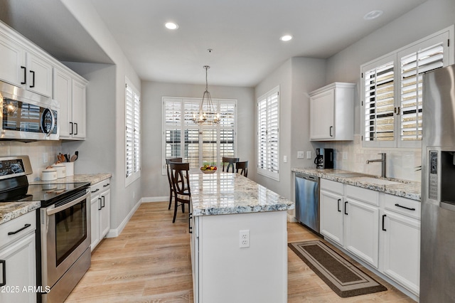 kitchen with a kitchen island, sink, white cabinetry, and stainless steel appliances