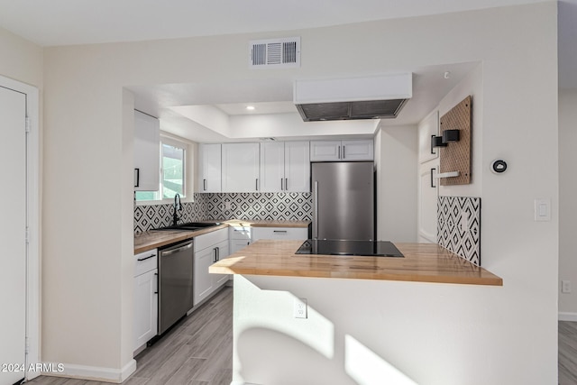 kitchen with sink, stainless steel appliances, wooden counters, white cabinets, and light wood-type flooring