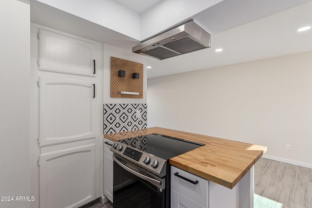 kitchen featuring butcher block counters, exhaust hood, light hardwood / wood-style flooring, electric range, and white cabinetry