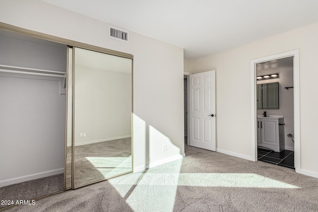 unfurnished bedroom featuring ensuite bath, a closet, and carpet