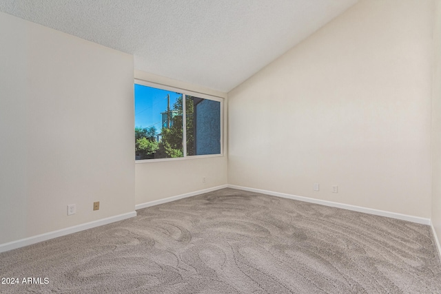 spare room with a textured ceiling, carpet floors, and lofted ceiling