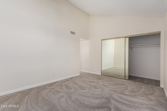 unfurnished bedroom featuring a closet, carpet, and high vaulted ceiling