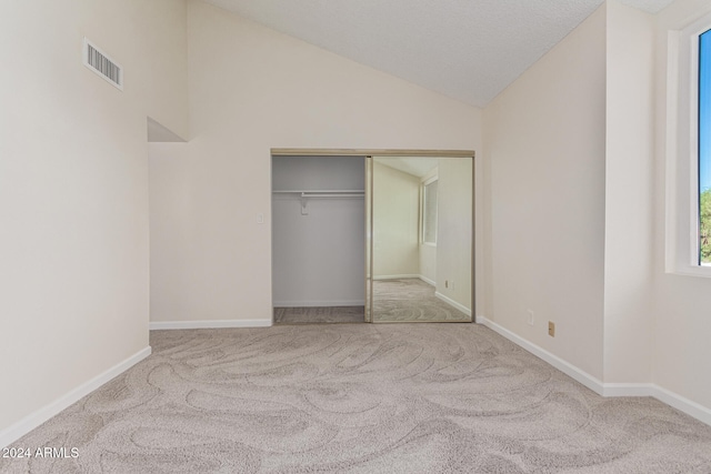 unfurnished bedroom with a closet, light colored carpet, and vaulted ceiling