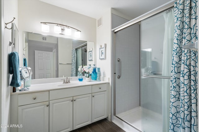 bathroom with hardwood / wood-style floors, vanity, and an enclosed shower