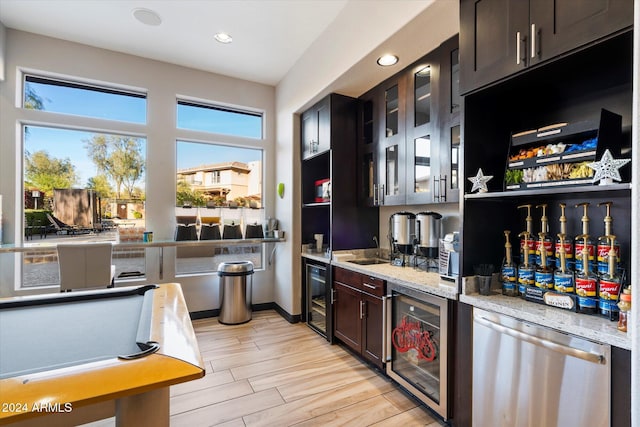 bar featuring stainless steel dishwasher, dark brown cabinets, light stone counters, and beverage cooler