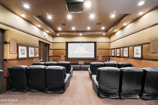 carpeted home theater featuring a tray ceiling and wooden walls