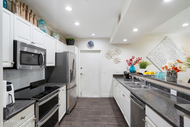 kitchen featuring sink, dark wood-type flooring, decorative backsplash, white cabinets, and appliances with stainless steel finishes