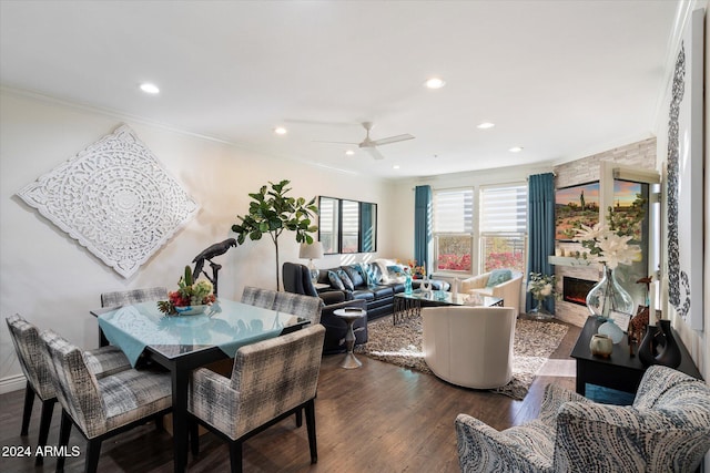 dining room featuring ceiling fan, a fireplace, crown molding, and dark hardwood / wood-style floors