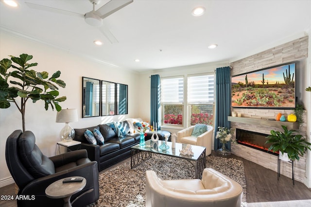 living room featuring a tile fireplace, ceiling fan, crown molding, and dark wood-type flooring