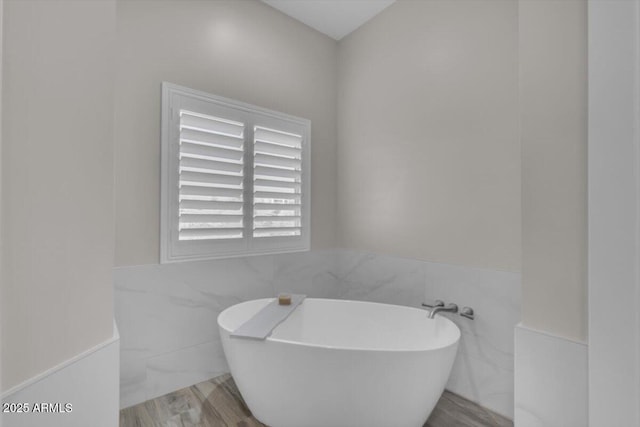 28319 N Marchant Trce, Queen Creek, AZ 85144 - bathroom featuring tile walls, wood finished floors, wainscoting, and a freestanding bath