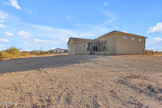 28319 N Marchant Trce, Queen Creek, AZ 85144 - back of house featuring a trampoline, stucco siding, and fence