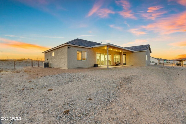 28319 N Marchant Trce, Queen Creek, AZ 85144 - back of house at dusk with roof with shingles, stucco siding, central air condition unit, and fence