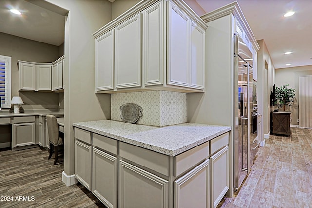 kitchen featuring light stone countertops, hardwood / wood-style floors, and decorative backsplash