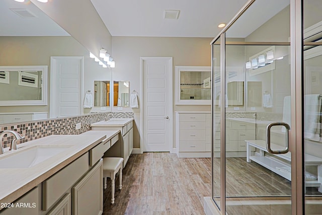 bathroom with decorative backsplash, hardwood / wood-style floors, vanity, and a shower with shower door